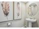 Stylish powder room with pedestal sink and decorative artwork at 2153 Flower Blossom Ave, Brighton, CO 80601