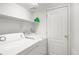 Bright laundry room with white washer and dryer, shelving and a closed door at 930 Button Rock Dr # 28, Longmont, CO 80504