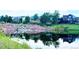 Picturesque view of a pond reflecting nearby houses, trees, and landscaped rocks, creating a serene and inviting environment at 6450 S Riverwood Ct, Aurora, CO 80016