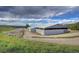Exterior view of a large barn with white fencing, gravel driveway, and picturesque landscape at 810 N Perry Park Rd, Sedalia, CO 80135
