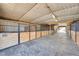 Interior of a horse barn with multiple stalls, concrete floor, and lighting fixtures at 810 N Perry Park Rd, Sedalia, CO 80135