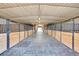 Inside horse barn with multiple stalls, concrete flooring, and bright lighting at 810 N Perry Park Rd, Sedalia, CO 80135