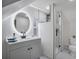 Modern bathroom with a gray vanity, frameless shower, and round mirror at 3545 W Custer Pl, Denver, CO 80219