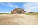 Back exterior view of a two-story home with covered porch, patio, and spacious backyard at 49346 E County Road 6, Bennett, CO 80102