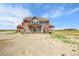Exterior back view showcasing covered porches and patio of a two-story home at 49346 E County Road 6, Bennett, CO 80102