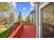 View of a large red wooden deck overlooking a lawn and mature trees, with a sliding glass door nearby at 10915 Acadia Ln, Parker, CO 80138