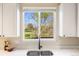 Bright kitchen featuring a garden window over the sink, hardwood floors, and white cabinets at 10915 Acadia Ln, Parker, CO 80138