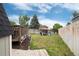 Large backyard featuring lush green grass, wooden fencing, and a cozy seating area for outdoor relaxation at 12104 Ivanhoe Ct, Brighton, CO 80602