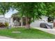 Charming single-story home featuring a well-maintained lawn, mature tree, and covered front porch with swing at 12104 Ivanhoe Ct, Brighton, CO 80602