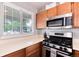 Bright kitchen featuring stainless steel appliances, wood cabinets, and a view to the outdoors through the window at 12104 Ivanhoe Ct, Brighton, CO 80602