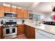 Well-equipped kitchen with stainless steel appliances, wood cabinets, and a view into the dining area at 12104 Ivanhoe Ct, Brighton, CO 80602