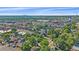 An aerial view shows mature trees, a home with a manicured lawn, and a cityscape in the distance at 5614 Yarrow St, Arvada, CO 80002