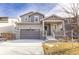 Charming two-story home features a covered porch, gray siding, stone accents, and attached two car garage at 10962 Vaughn St, Commerce City, CO 80022