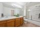 This bathroom includes wood cabinets, large mirror, bath and shower combination with sliding glass doors at 10166 Grove Loop # D, Westminster, CO 80031