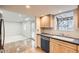 Cozy kitchen featuring stainless dishwasher, wood cabinets, and tile floors to the adjoining living area at 11864 E Idaho Dr, Aurora, CO 80012
