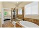 Bathroom featuring a glass-enclosed shower and soaking tub with tile surround and an open doorway to the bedroom at 8582 E 148Th Ln, Thornton, CO 80602