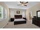 Spacious bedroom with a ceiling fan, shuttered windows, carpet, and ensuite bathroom partially visible through open door at 8582 E 148Th Ln, Thornton, CO 80602