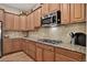 Granite counters and tiled backsplash highlight this updated kitchen with wooden cabinetry at 8582 E 148Th Ln, Thornton, CO 80602