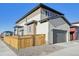 A modern two-story home with a garage, wooden fence, and stone accents in the backyard at 21185 E 62Nd Ave, Aurora, CO 80019