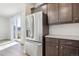 Modern stainless steel refrigerator in a kitchen with dark wood cabinets and a view to the outside at 21185 E 62Nd Ave, Aurora, CO 80019