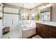 Bathroom featuring dual sinks, soaking tub, glass shower, and large window at 8487 S Nelson St, Littleton, CO 80127