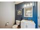Stylish half-bathroom with modern fixtures, white vanity, and a contrasting blue accent wall at 8487 S Nelson St, Littleton, CO 80127