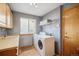 Functional laundry room with tile floors, appliances, cabinets, and a window at 8487 S Nelson St, Littleton, CO 80127