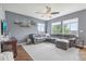 Spacious living room featuring hardwood floors, large windows, and a comfortable gray sectional sofa at 16226 W 94Th Dr, Arvada, CO 80007