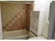 Bathroom featuring a tub-shower with brown and tan tile surround and white storage shelves to the side at 14503 E Wagon Trail Dr, Aurora, CO 80015