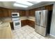 Eat in kitchen with warm wood cabinetry, tile floors and stainless steel refrigerator at 14503 E Wagon Trail Dr, Aurora, CO 80015