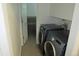 Modern laundry room featuring gray tile flooring, side-by-side washer and dryer units, and ample cabinet space at 14503 E Wagon Trail Dr, Aurora, CO 80015