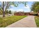 Charming red brick home featuring a well-manicured lawn and a convenient covered carport at 2201 Lima St, Aurora, CO 80010