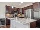 Stylish kitchen island featuring granite countertops, a stainless steel fridge, and modern lighting fixtures at 15079 E Poundstone Pl, Aurora, CO 80015