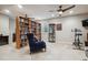 Living room features bookshelves, ceiling fans, comfortable arm chair, and exercise equipment at 15079 E Poundstone Pl, Aurora, CO 80015