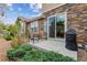 Cozy patio with outdoor seating and a grill, complemented by lush greenery and a stone exterior at 15079 E Poundstone Pl, Aurora, CO 80015