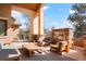 Elegant outdoor living space featuring a stone fireplace and comfortable seating under a covered patio at 651 Ruby Trust Dr, Castle Rock, CO 80108