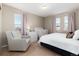 A neutral bedroom featuring a queen bed, crib, and sitting chair at 35 N Newcastle Ct, Aurora, CO 80018