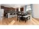 Open kitchen featuring dark wood cabinets, hardwood floors, stainless steel appliances, and breakfast bar with adjacent dining area at 35 N Newcastle Ct, Aurora, CO 80018
