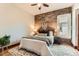 Comfortable bedroom with a brick accent wall, plush rug, and natural light from the window at 1012 Fillmore St, Denver, CO 80206