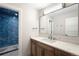 Beautiful bathroom features a blue tiled walk-in shower, white countertops, and wooden cabinets for storage at 2237 S Madison St, Denver, CO 80210