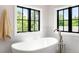 Bright bathroom featuring a standalone tub with black frame windows overlooking lush greenery at 2237 S Madison St, Denver, CO 80210