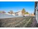 Large, fenced backyard with lush grass and mature trees, creating a private outdoor space for enjoyment at 6369 W 69Th Ave, Arvada, CO 80003