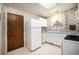 Cozy kitchen featuring white cabinetry and appliances, a skylight, and wallpaper at 6369 W 69Th Ave, Arvada, CO 80003