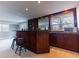 Wet bar in basement with wood cabinetry, mirror backsplash, stools, and additional counter space at 126 Mc Intyre Circle, Golden, CO 80401