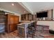 Basement bar area with stone countertop, wooden cabinets and walls, and TV at 22025 Oehlmann Park Rd, Conifer, CO 80433