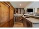Basement bar area features stone countertops, wooden cabinets, bar stools, and wooden walls at 22025 Oehlmann Park Rd, Conifer, CO 80433
