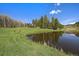 Picturesque pond reflecting the beautiful home and tree lined landscape on a sunny day at 22025 Oehlmann Park Rd, Conifer, CO 80433