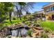 View of the manicured backyard featuring a custom pond with water features, beautiful landscaping and a manicured lawn at 5020 W Quarles Dr, Littleton, CO 80128
