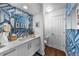 Stylish powder room with modern vanity, decorative mirror, and patterned wallpaper at 5020 W Quarles Dr, Littleton, CO 80128