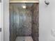 Modern walk-in shower with glass door and unique tile, enhancing the bathroom's design at 5020 W Quarles Dr, Littleton, CO 80128